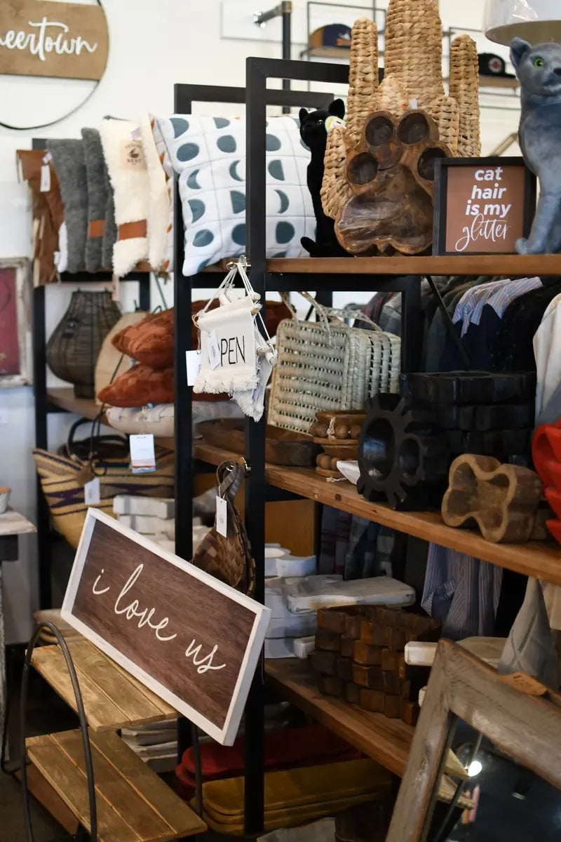 Metal shelves of pillows, baskets and gifts with an "i love us" sign