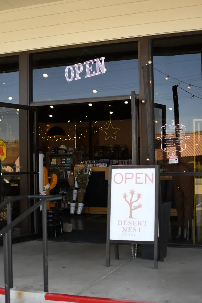 Desert Nest Co. front door with a neon OPEN sign and sandwich board